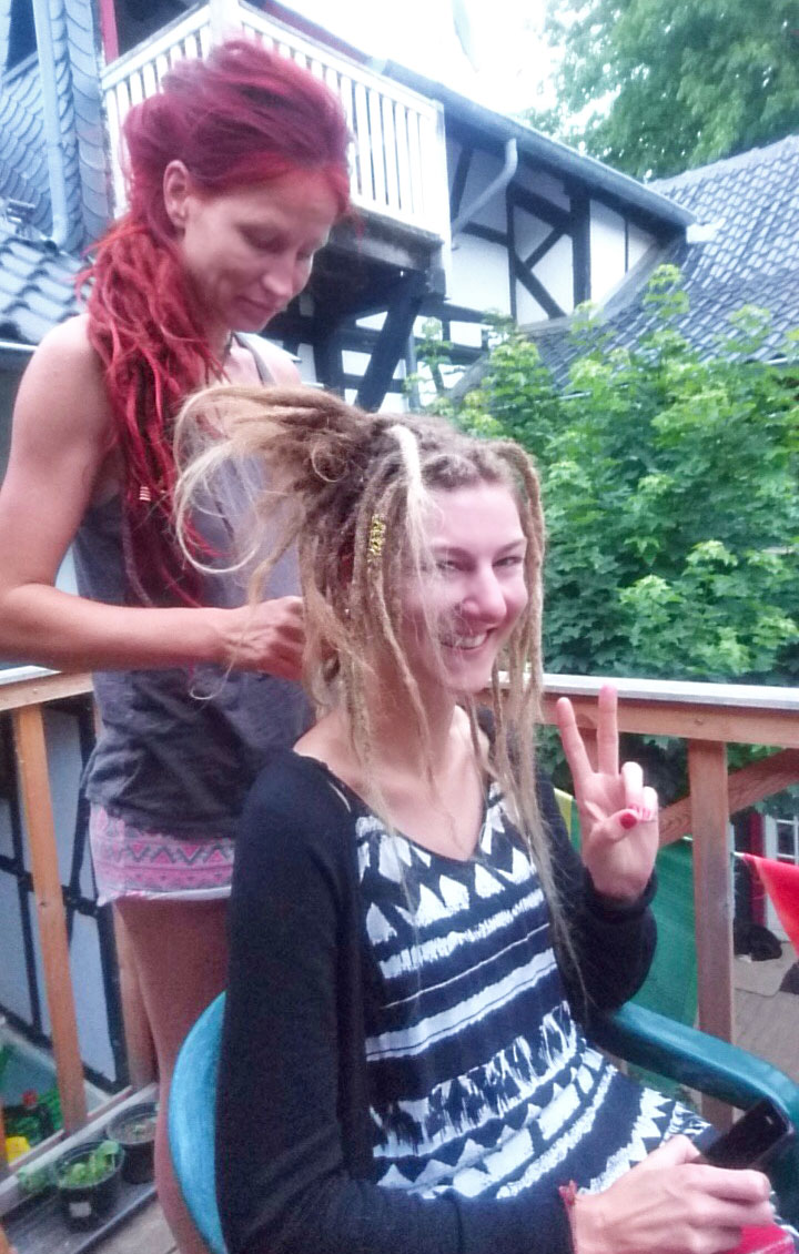 Red dreadhead adding extensions to blonde rasta girl's hair near Cologne, Germany