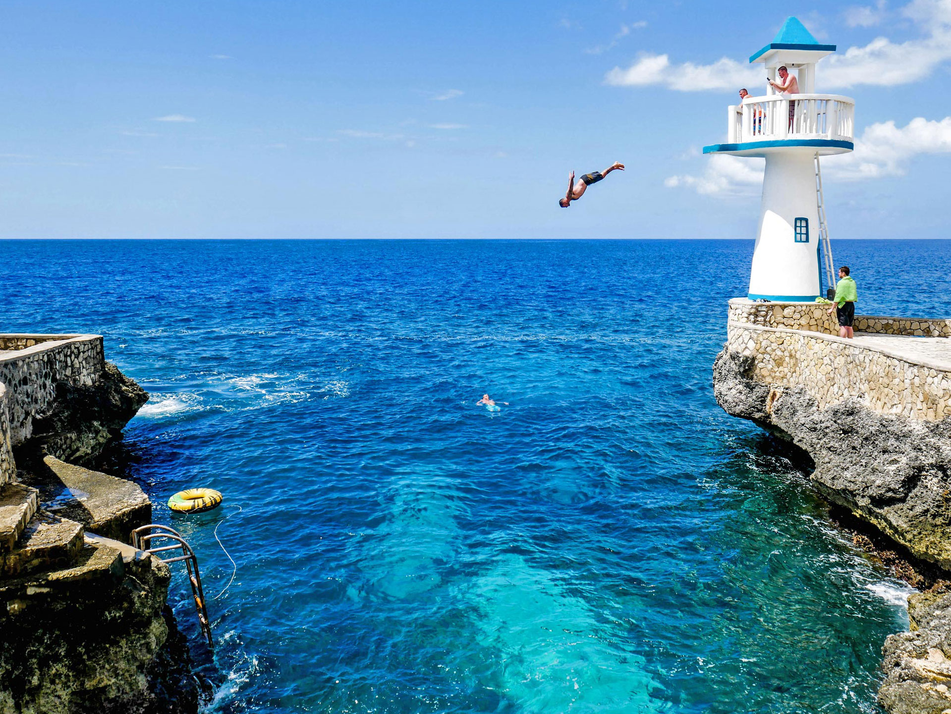 Guests diving from the lighthouse into ocean at cliff hotel in West End, Jamaica