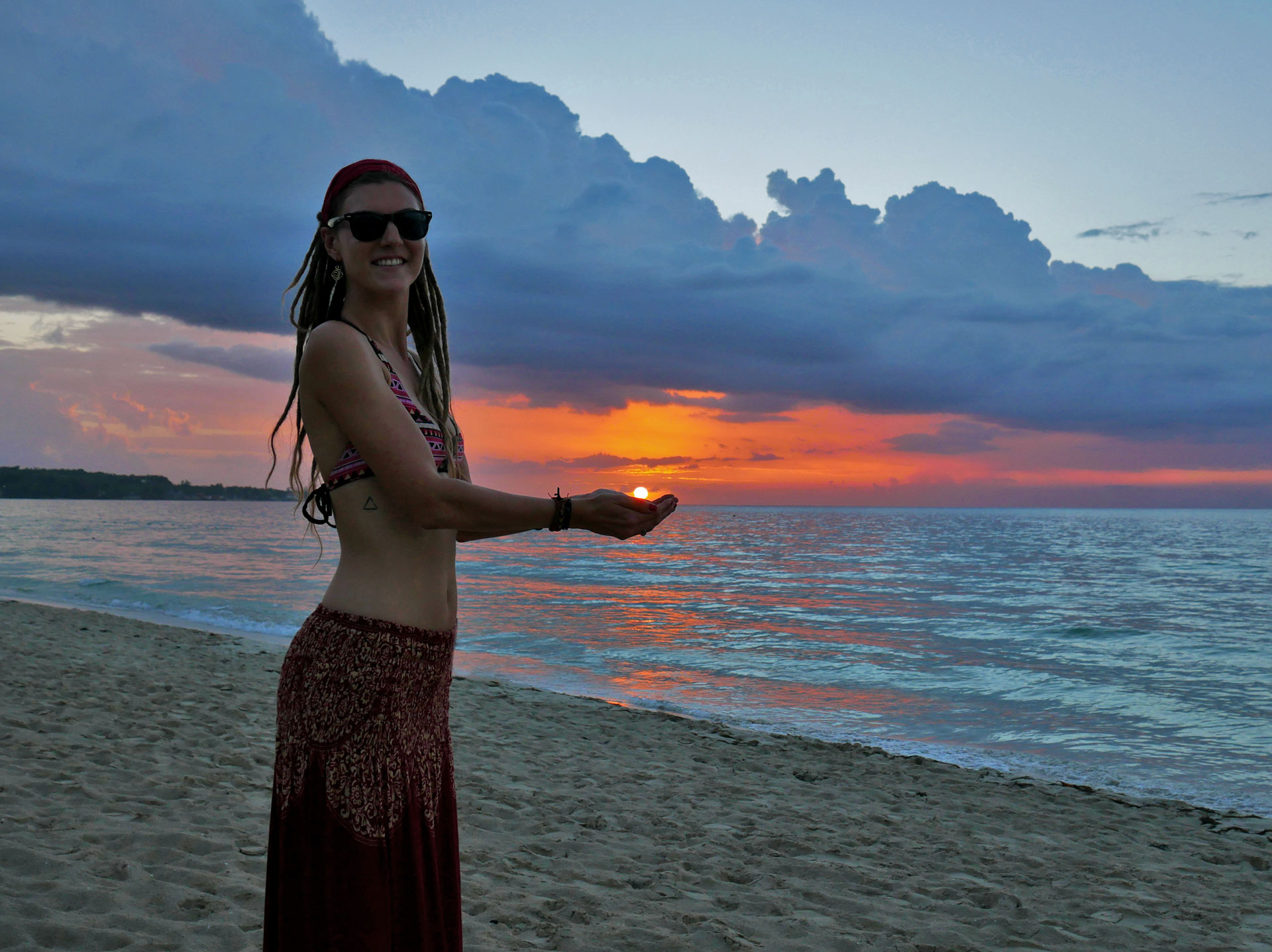 Rasta girl holding setting sun at Seven Mile Beach, Negril, Jamaica