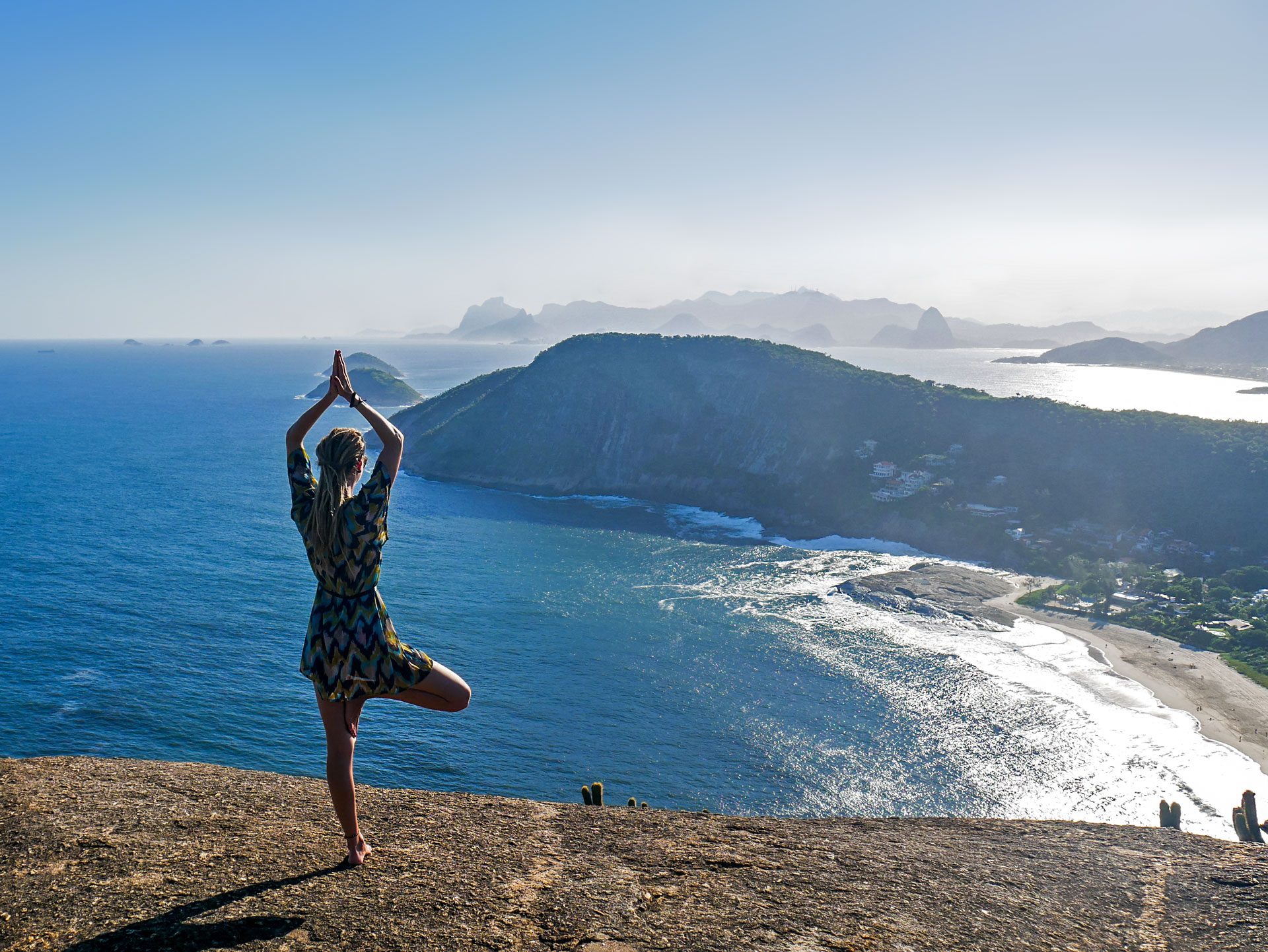 Rasta girl doing yoga on top of mountain in Itacoatiara, Brazil