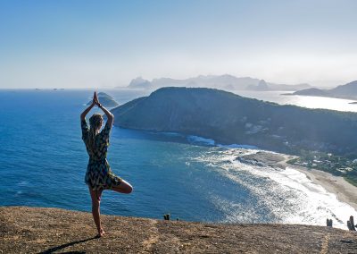 Rasta girl doing yoga on top of mountain in Itacoatiara, Brazil