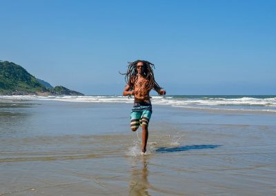 Rastaman running at beach in Barra do Una, Brazil