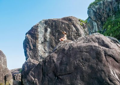 Rasta girl meditating on cliff in Barra do Una, Brazil