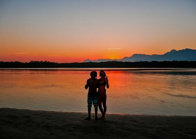 Rasta couple in front of river during sunset in Barra do Una, Brazil