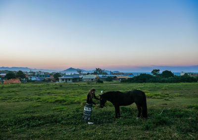 Rasta girl with horse in front of sunset over Ribanceira, Imbituba, Brazil