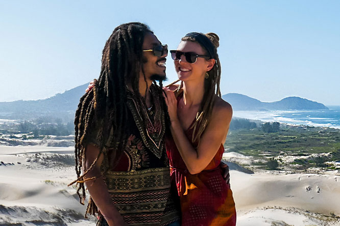 Dreadlock couple laughing in Dunas da Ribanceira with ocean view in Imbituba, Brazil